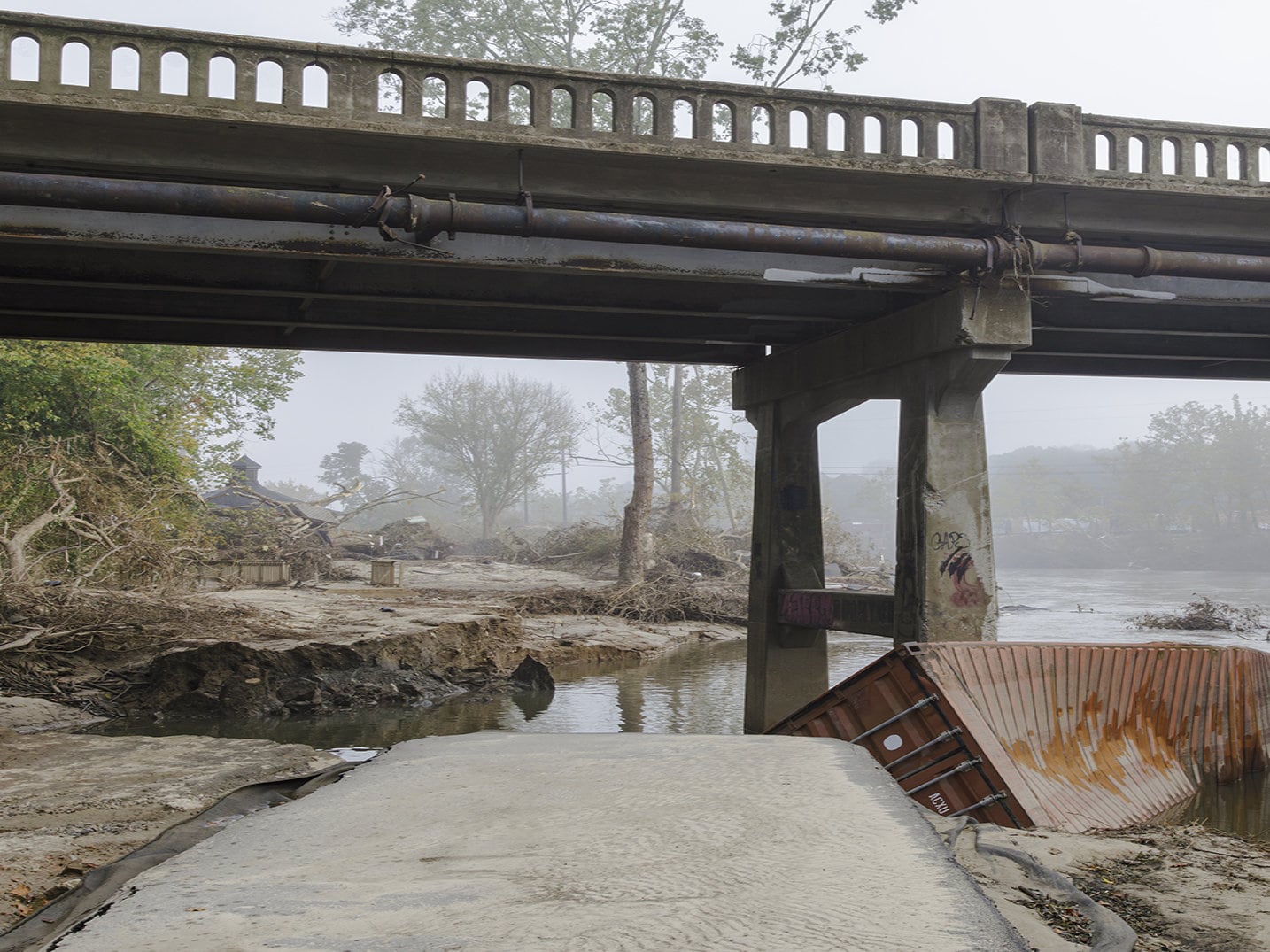 destroyed greenway with mangled shipping container and debris