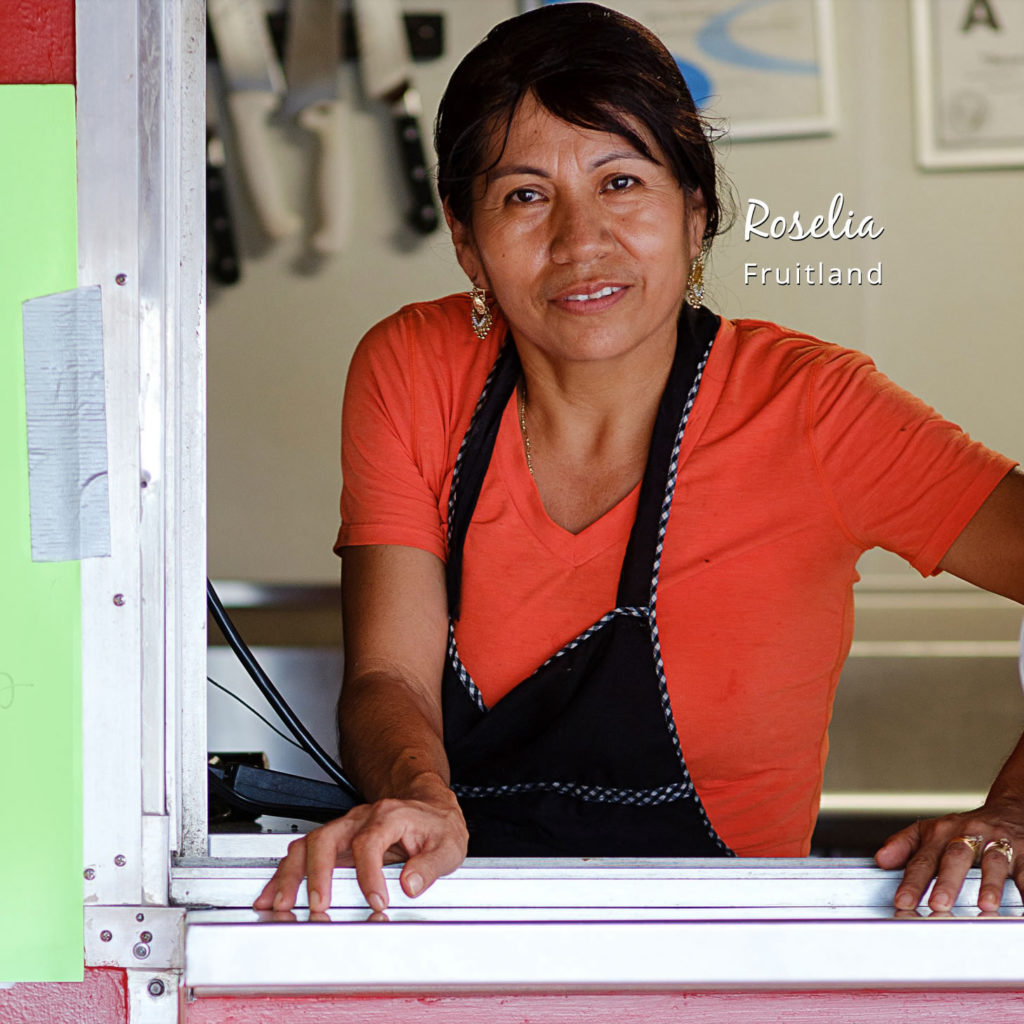 Hispanic woman in a back apron leaning out of a food truck with the text "Roselia, Fruitland".