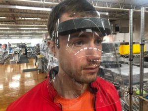 Plant worker wearing face shield while working in warehouse.