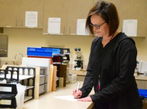 Nurse in black scrubs fills out paper work in medical office