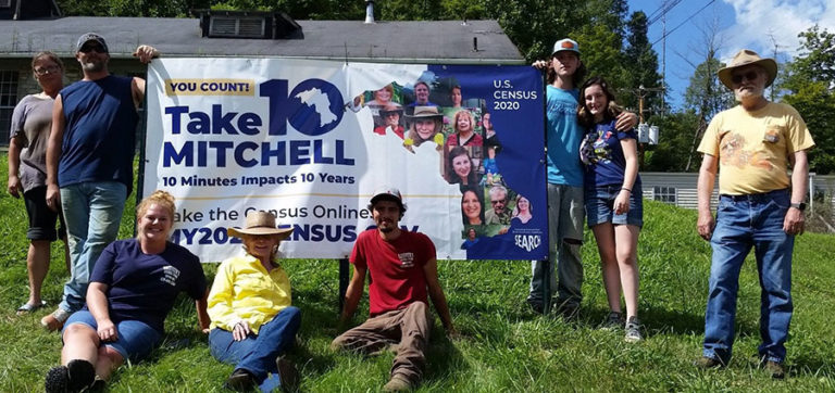 Group of people posing with a banner that says "Take 10 Mithcell" promoting the 2020 Census.