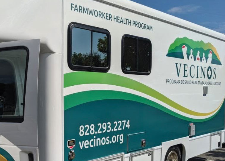 Outside of the Vecinos Mobile unit with logo and green to yellow swooshes.