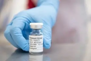 Close up of a sample tube being held by a glvoed hand.