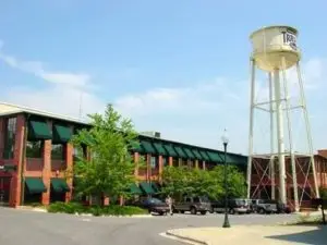 2 story brick building with small water tower in the font and dark green awnings over the windows.