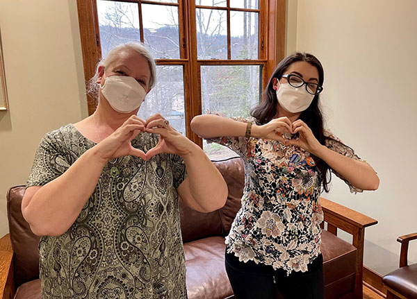 Women wearing masks holding up hand hearts