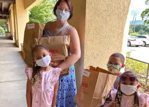 Woman with 3 kids holding paper grocery bags