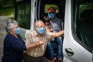 Elderly man being helped into a van by an elderly woman