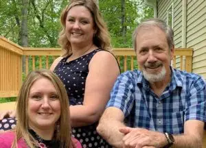 2 women and 1 man sitting on porch smiling