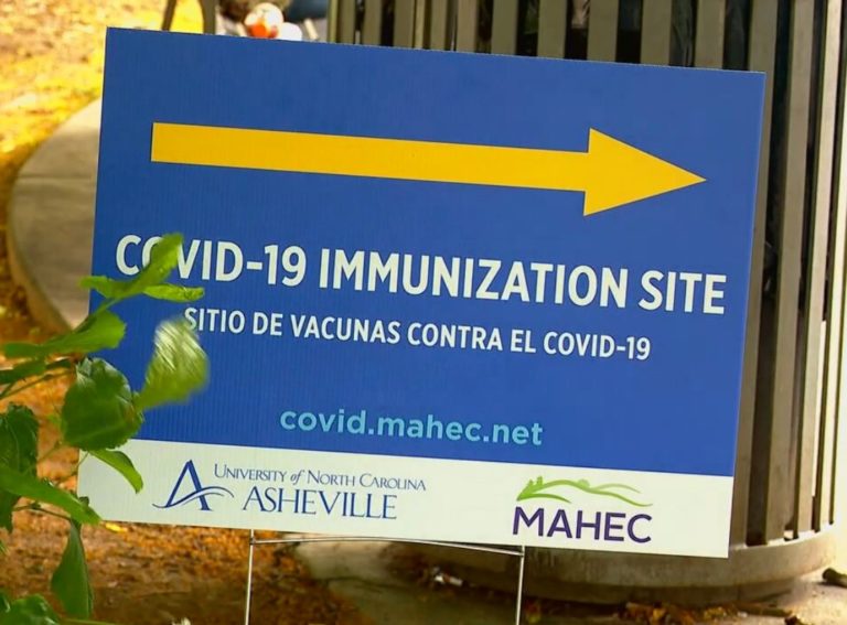 Blue Covid-10 Immunization Site sign with yellow arrow