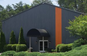 Exterior of dark grey building with vertical orange stripe on side.