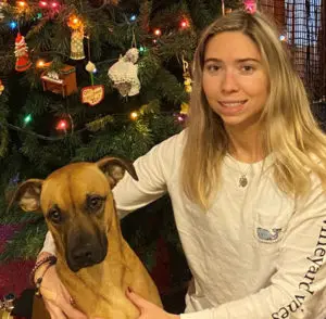 Woman standing with dog infront of Christmas tree