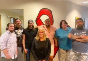 The Harm reduction team standing for a group photo in front of a red ribbon painting