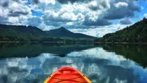 POV of person in an orange kayak on a mountain lake