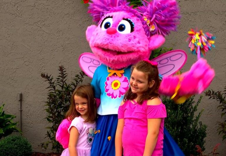 two girls posing with Sesame Street character