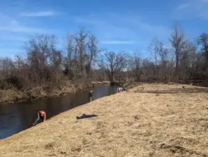 Volunteers picking up trash along the Mills River bank