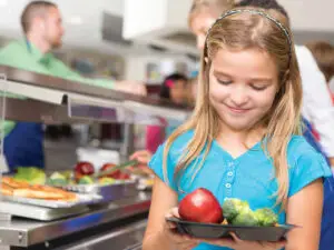 Youung girl smiling at a plate of fruits and vegetables