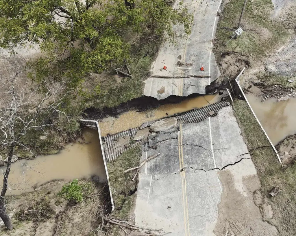 Aerial view of a collapsed road over a muddy creek formed by stormwater from Hurricane Helene