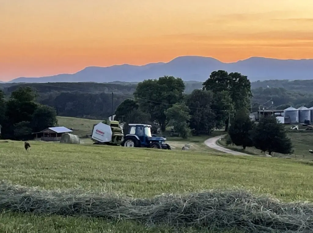 tractor in farm field with colorful sunset