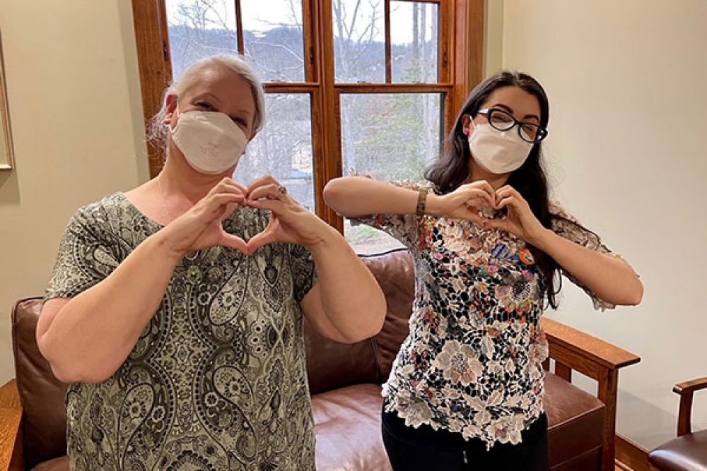 Women wearing masks holding up hand hearts