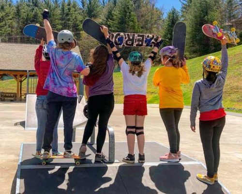 Group of girls at a skate park with colorful helmets and skateboards
