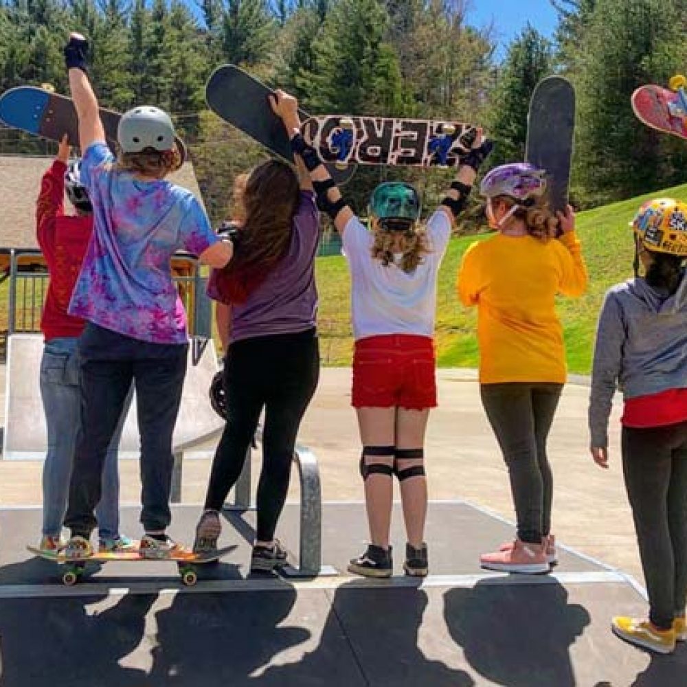 Group of girls at a skate park with colorful helmets and skateboards