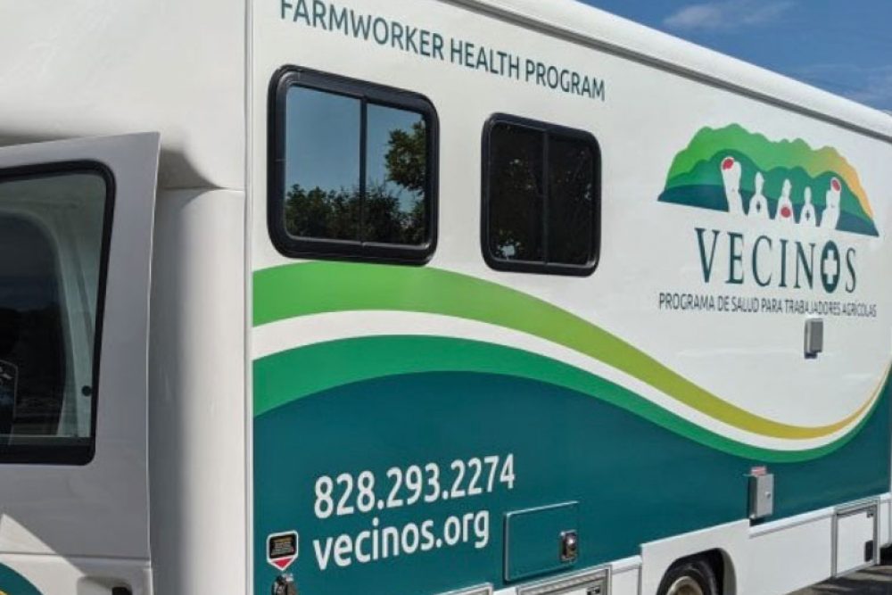 Outside of the Vecinos Mobile unit with logo and green to yellow swooshes.