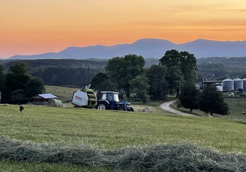 farming tractor in a field at sunset